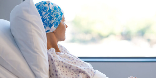 Mujer con cáncer mirando por la ventana.